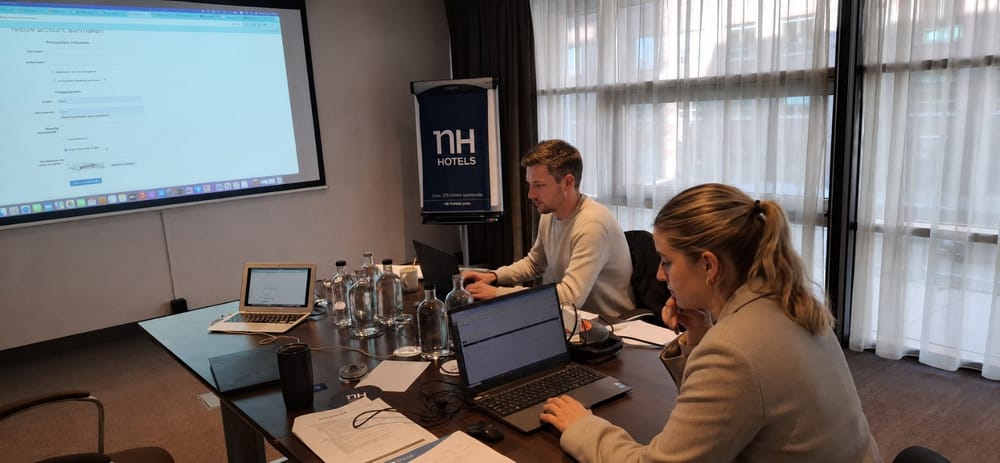 Twee cursisten werken op laptops tijdens een training in een vergaderruimte