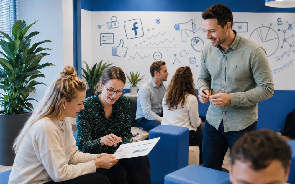 Cursisten overleggen in een ruimte met social-media-illustraties en het Facebook-logo tijdens de Facebook-cursus