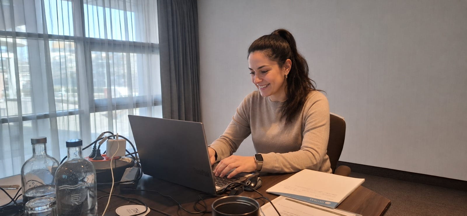 Cursist volgt een training op haar laptop aan een bureau bij het raam