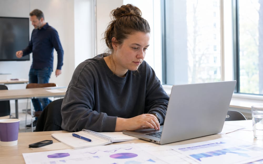 Cursist werkt op een laptop aan data-analyses met grafieken op tafel tijdens de R-training
